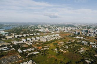 Vista aérea de Brasília, com áreas verdes, edifícios e o traçado urbano da capital federal