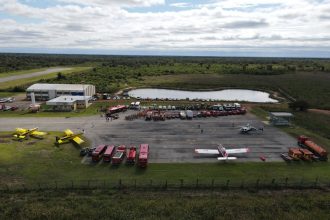 Vista aérea de uma base de combate a incêndios com aeronaves, caminhões e equipes de emergência.
