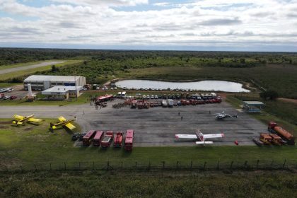 Vista aérea de uma base de combate a incêndios com aeronaves, caminhões e equipes de emergência.