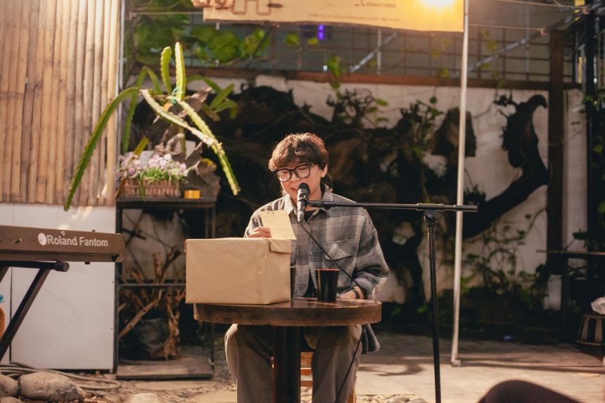 Jovem artista faz leitura de poesia ao ar livre usando um microfone